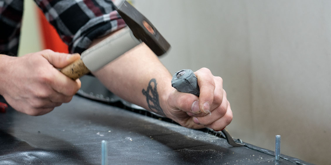 Polsterer takelt den alten Lederbezug vom Flasche Sofa mit Polsterwerkzeug ab