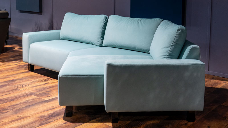 seitliche Ansicht von Sofa Delta in unseren Showroom, es ist bezogen im hellbaluen weichen Stoff
